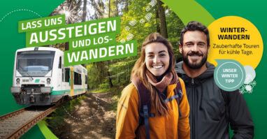 Zwei Menschen steigen aus der Vogtlandbahn im Wald aus, bereit für eine Wanderung.